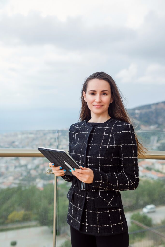 blogger girl is looking camera by holding planshet computer against background city view